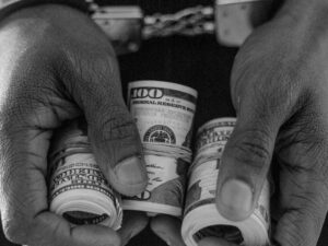 person in handcuff holding rolled dollar bills