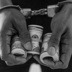 person in handcuff holding rolled dollar bills